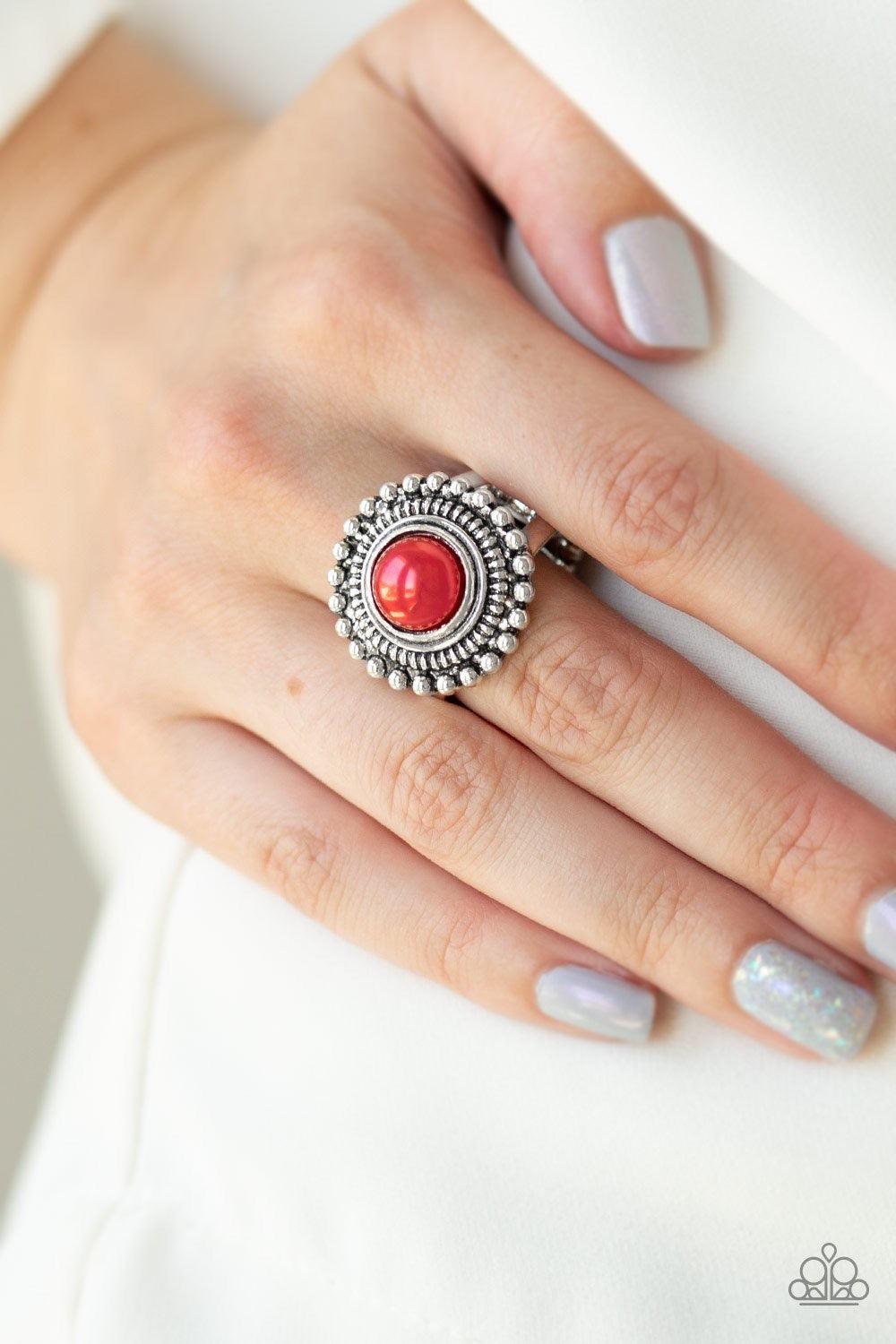 Paparazzi Accessories Regal Royal - Red A roung red bead is pressed into the center of a textured silver frame radiating in a ring of silver studs for a whimsical pop of color. Features a stretchy band for a flexible fit. Jewelry