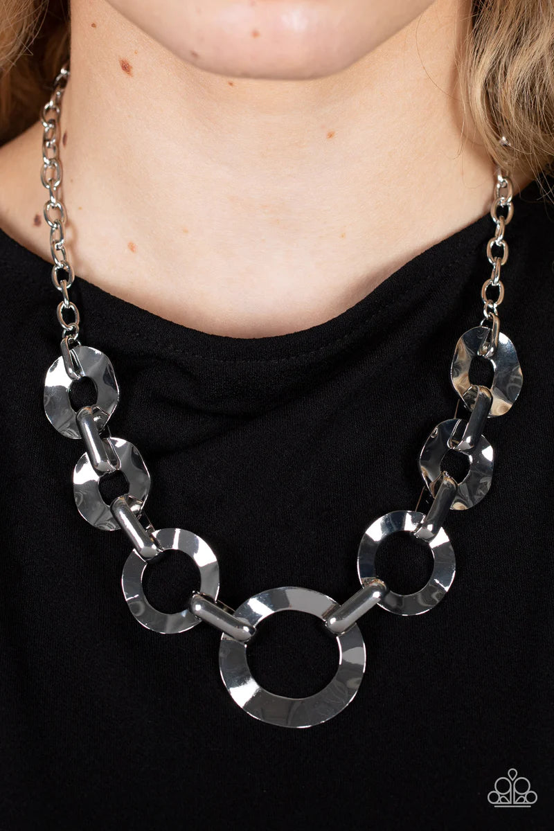 Paparazzi Accessories Mechanical Masterpiece - Silver Featuring hammered surfaces, crinkled silver rings gradually increase in size as they alternate with bold silver fittings below the collar for an intense industrial fashion. Features an adjustable clas