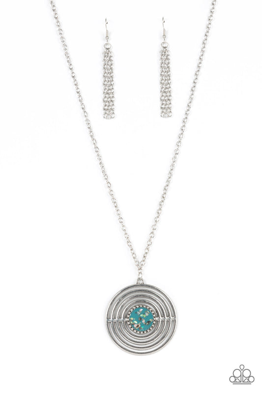 Paparazzi Accessories Targeted Tranquility - Blue Flecked in iridescent shell-like accents, a studded blue frame adorns the center of an oversized silver pendant rippling with concentric circles at the bottom of an extended silver chain for a dizzying pop