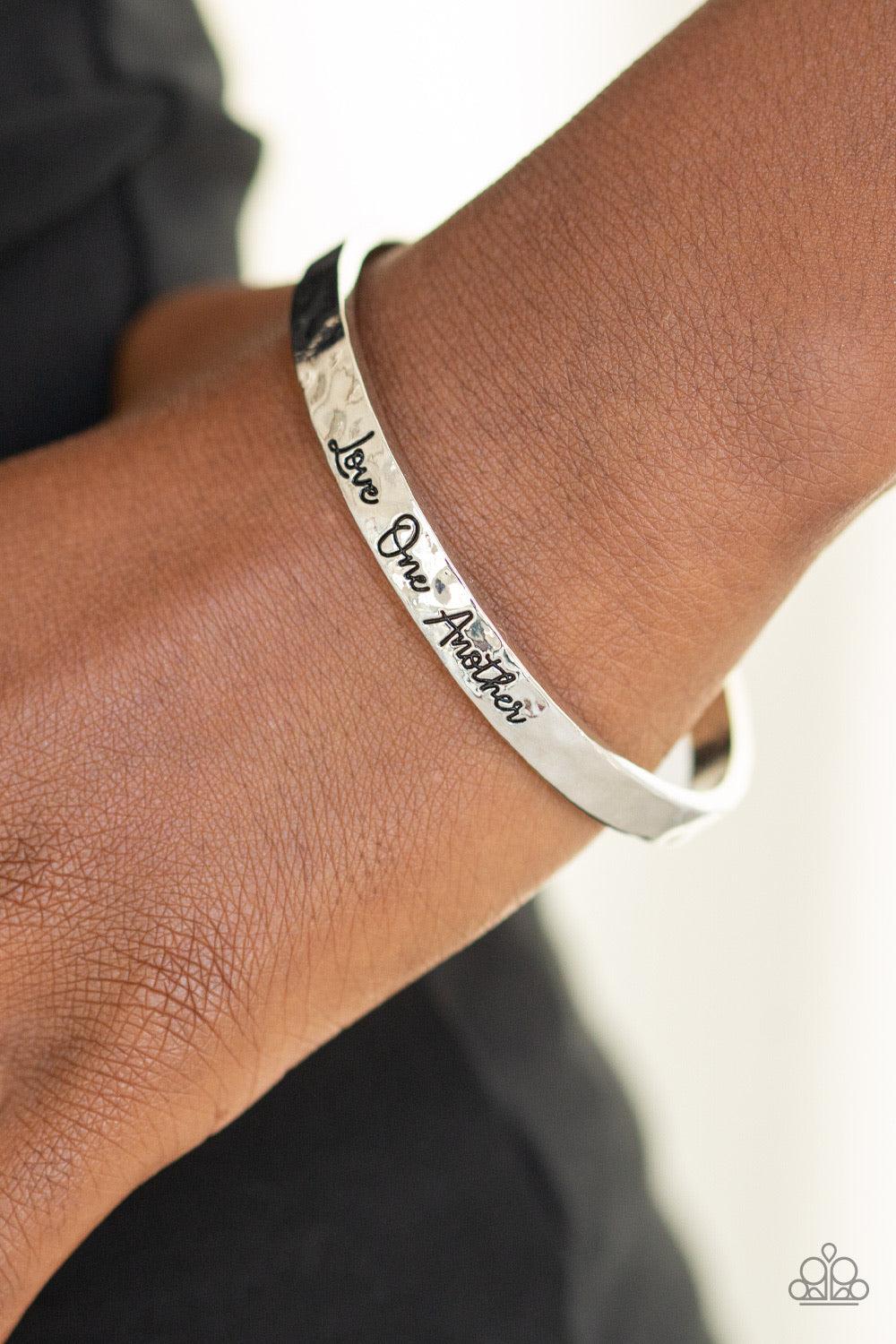 Paparazzi Accessories Love One Another ~Silver Delicately hammered in shimmery textures, a dainty silver cuff is stamped in the phrase, "Love One Another", for an inspirational finish.