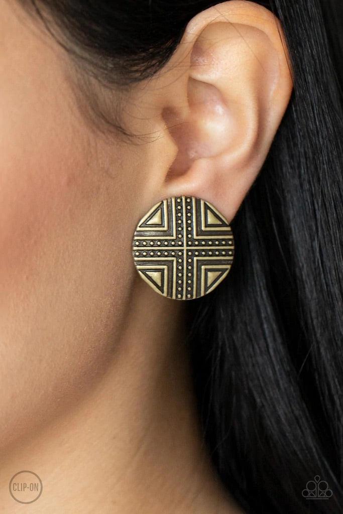 Paparazzi Accessories Shielded Shimmer - Brass *Clip-On Brushed in an antiqued shimmer, a round brass frame is studded and embossed in crisscrossed geometric patterns for an indigenous look. Earring attaches to a standard clip-on fitting. Sold as one pair