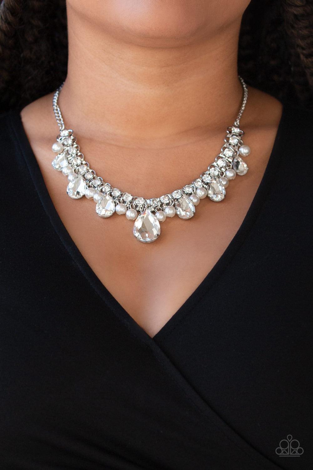 Paparazzi Accessories Knockout Queen - White A glamorous collection of bubbly white pearls and exaggerated white teardrop gems dangle from a bold strand of white rhinestones, creating a knockout fringe below the collar. Features an adjustable clasp closur