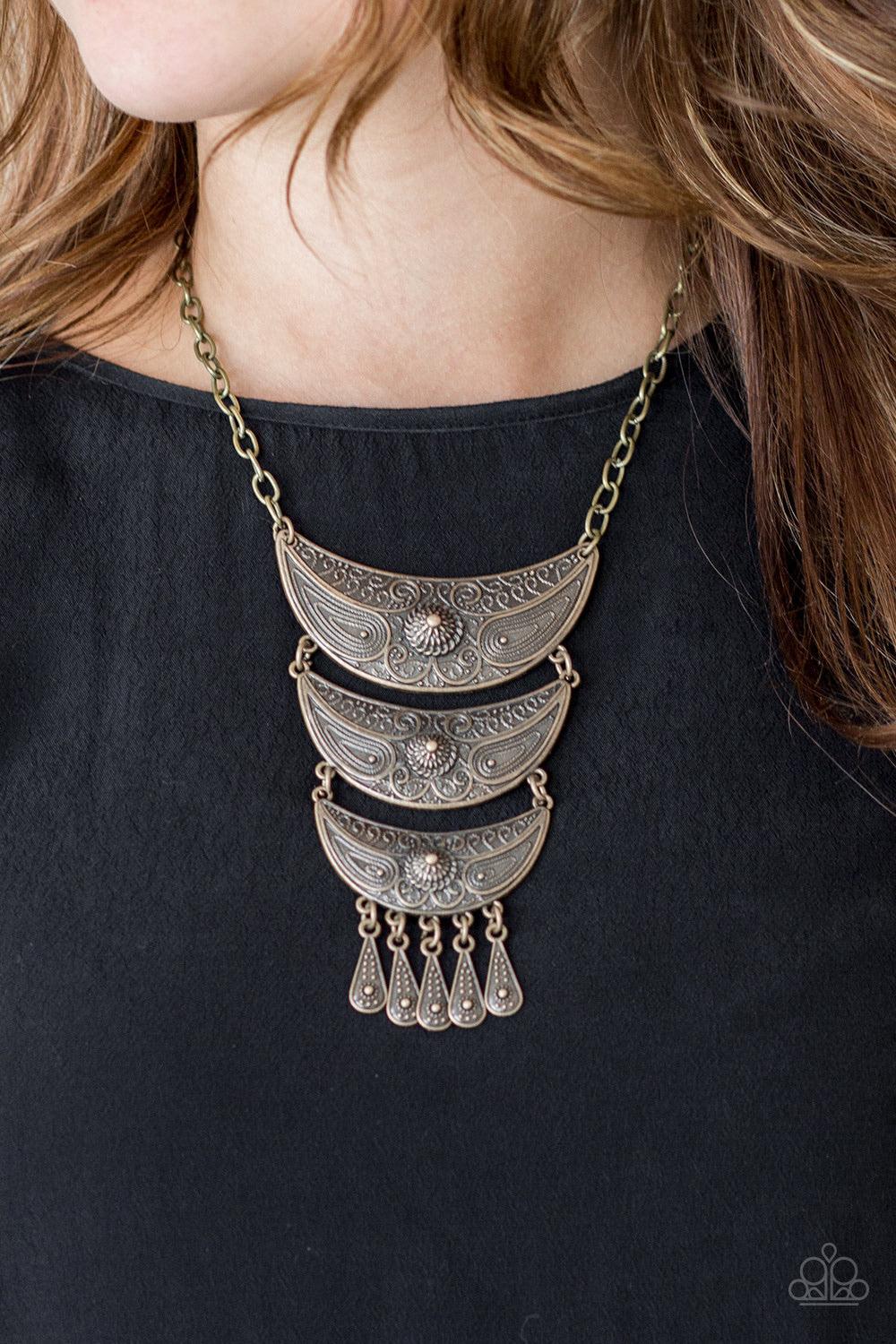 Paparazzi Accessories Go STEER - Crazy - Brass Gradually decreasing in size down the chest, decorative brass crescent plates connect into a bold pendant. Dotted in dainty studs, teardrop brass frames swing from the bottom of the tribal inspired pendant fo