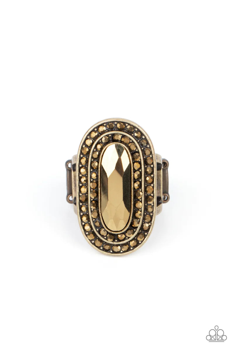Paparazzi Accessories Fueled by Fashion - Brass An elongated sparkling aurum gem is nestled inside a linear brass frame created by double rows of dainty aurum rhinestones. The faceted gem creates a glamorously edgy effect atop the finger. Features a stret