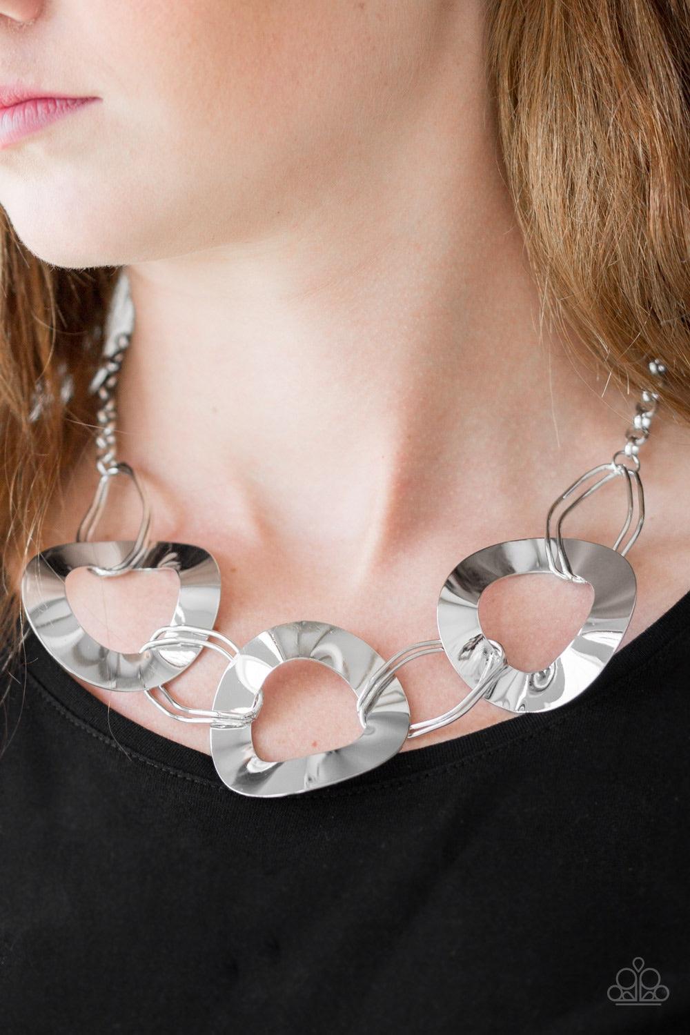 Paparazzi Accessories Modern Mechanics - Silver Featuring slightly warped surfaces, asymmetrical silver hoops link with reflective silver rings below the collar for a modern look. Features an adjustable clasp closure. Jewelry