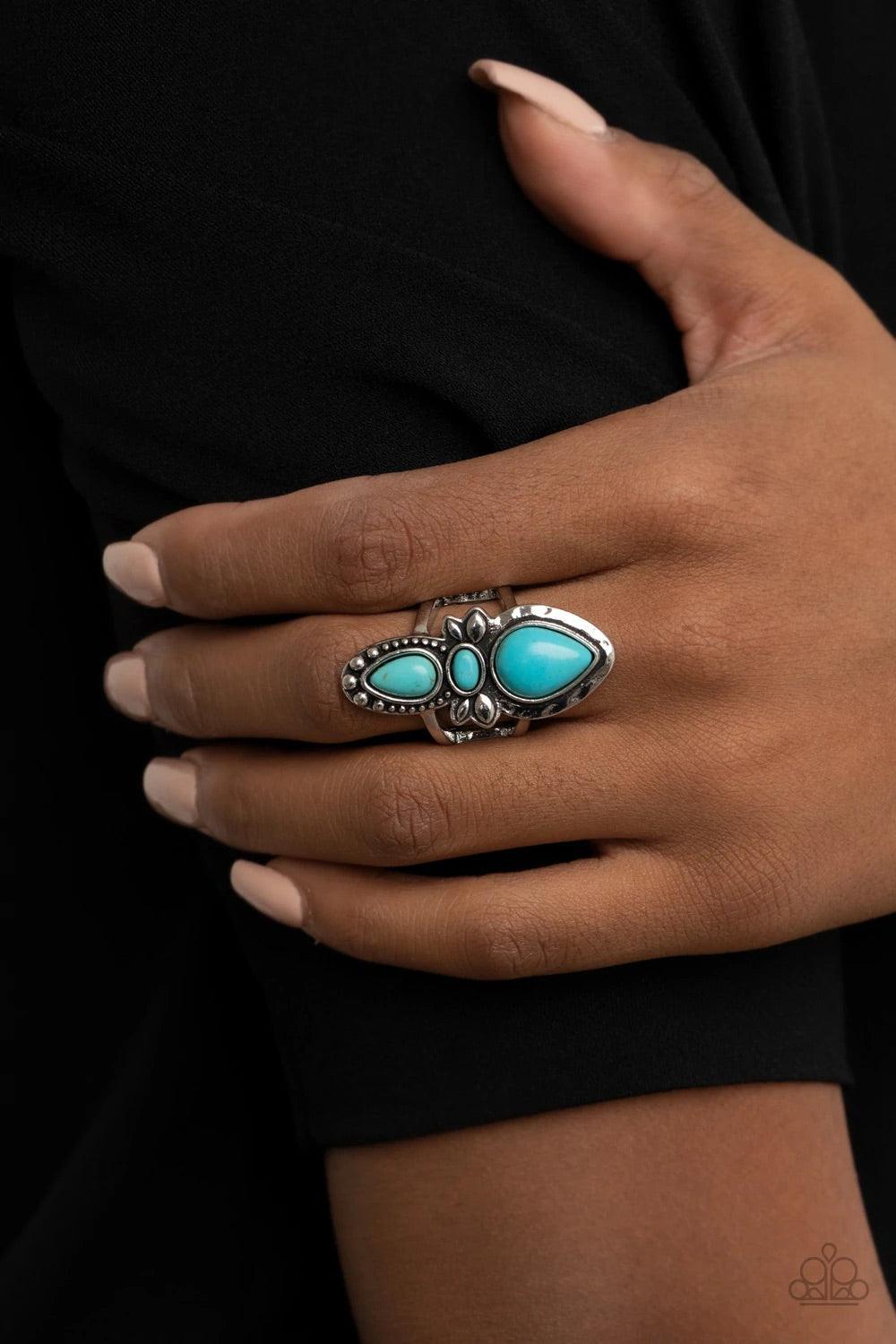 Paparazzi Accessories In a BADLANDS Mood - Blue Two refreshing turquoise stone teardrops flank a dainty oval turquoise stone and decoratively studded and hammered silver frame, creating a rustic statement piece atop the finger. Features a stretchy band fo