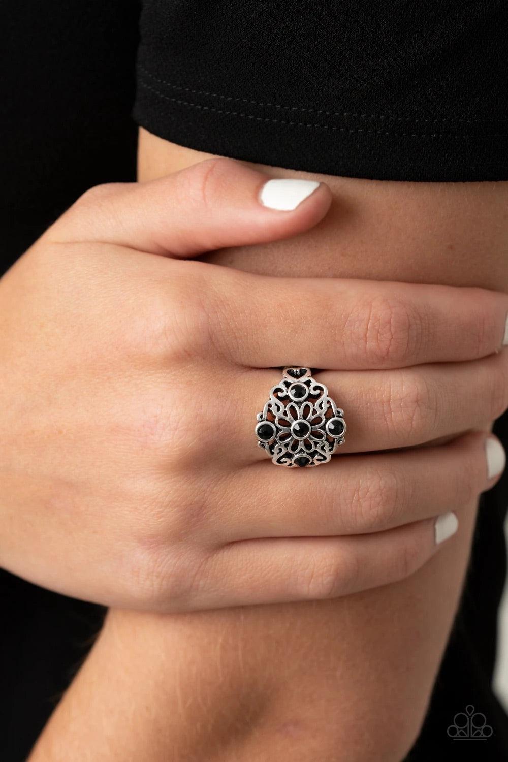 Paparazzi Accessories One DAISY At A Time - Black Dotted with glittery black rhinestones, glistening silver filigree blooms into a whimsical floral centerpiece atop the finger. Features a stretchy band for a flexible fit. Sold as one individual ring. Jewe