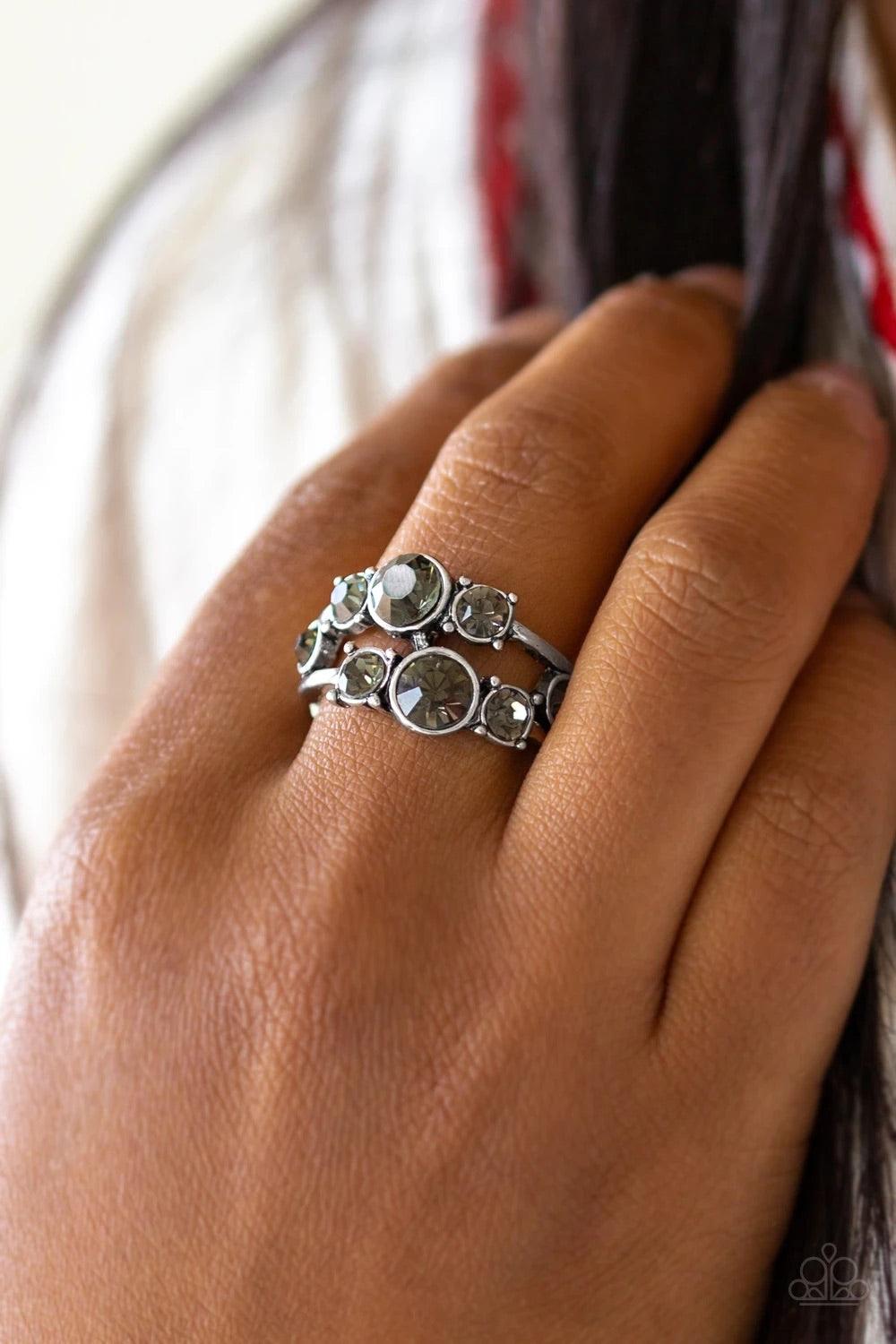 Paparazzi Accessories Interstellar Fashion - Silver Rows of smoky rhinestones connect across the finger, coalescing into a glamorous band. Features a dainty stretchy band for a flexible fit. Sold as one individual ring. Rings