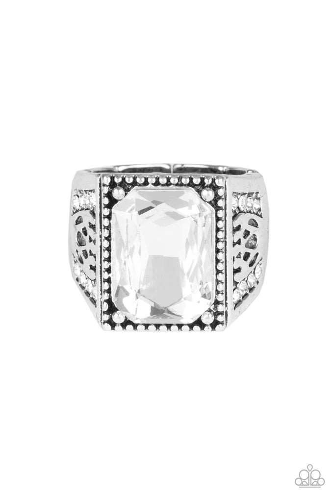 Paparazzi Accessories Conquered - White Featuring an emerald style cut, a white gem is pressed into the center of a studded silver frame featuring an ornate silver band encrusted in sections of white rhinestones. Features a stretchy band for a flexible fi