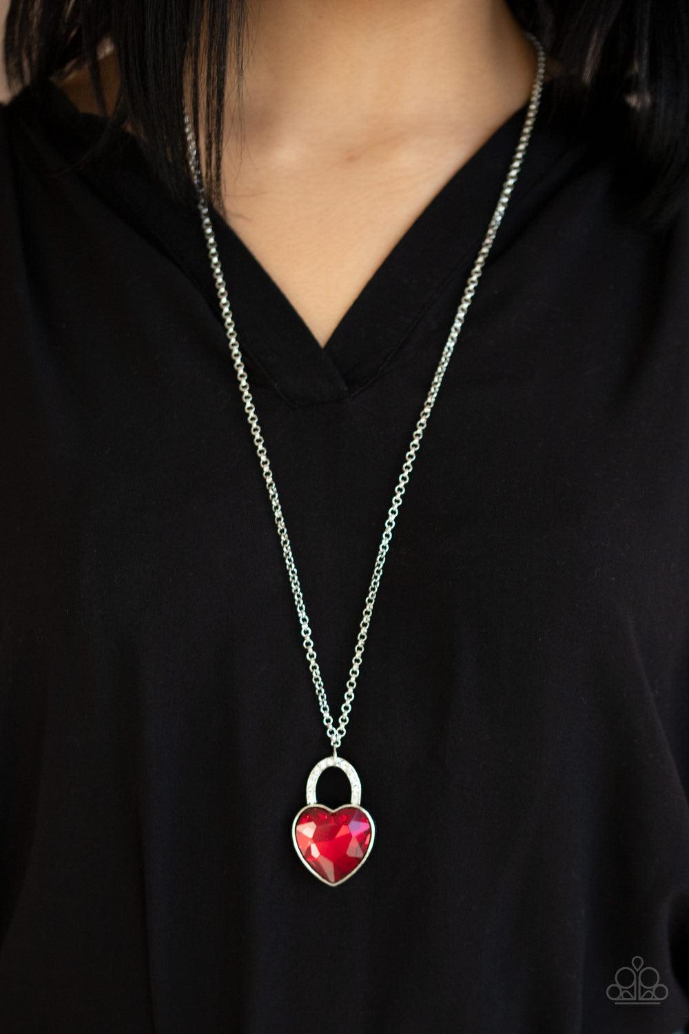 Paparazzi Accessories Locked In Love - Red Chiseled into a charming heart, an oversized red gem is pressed into a silver frame radiating with glassy white rhinestones, creating a glamorous pendant at the bottom of a lengthened silver chain. Features an ad