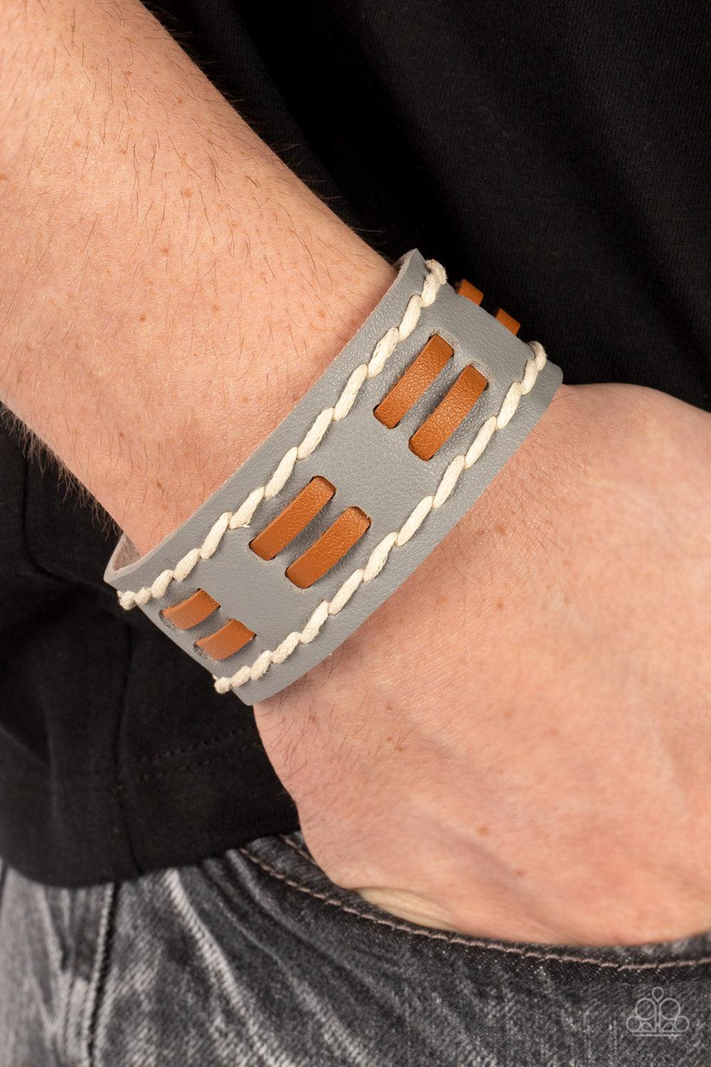 Paparazzi Accessories In the FRONTIER Running - Silver Flanked with two stitched rows, two rows of brown leather laces are threaded through the center of a gray leather band for a rustic pop of color around the wrist. Features an adjustable snap closure.