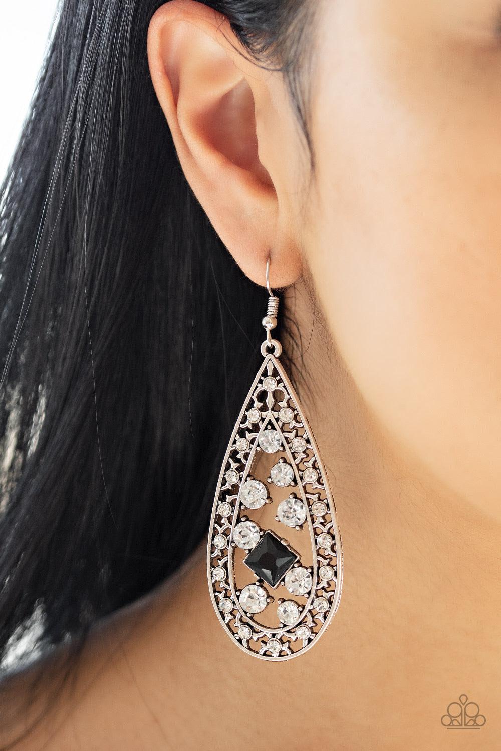 Paparazzi Accessories Drop-Dead Dazzle - Black A glassy collection of white rhinestones coalesce inside the center of a white rhinestone encrusted silver teardrop. Featuring a regal square cut, a glittery black rhinestone is added for a timeless twist. Ea