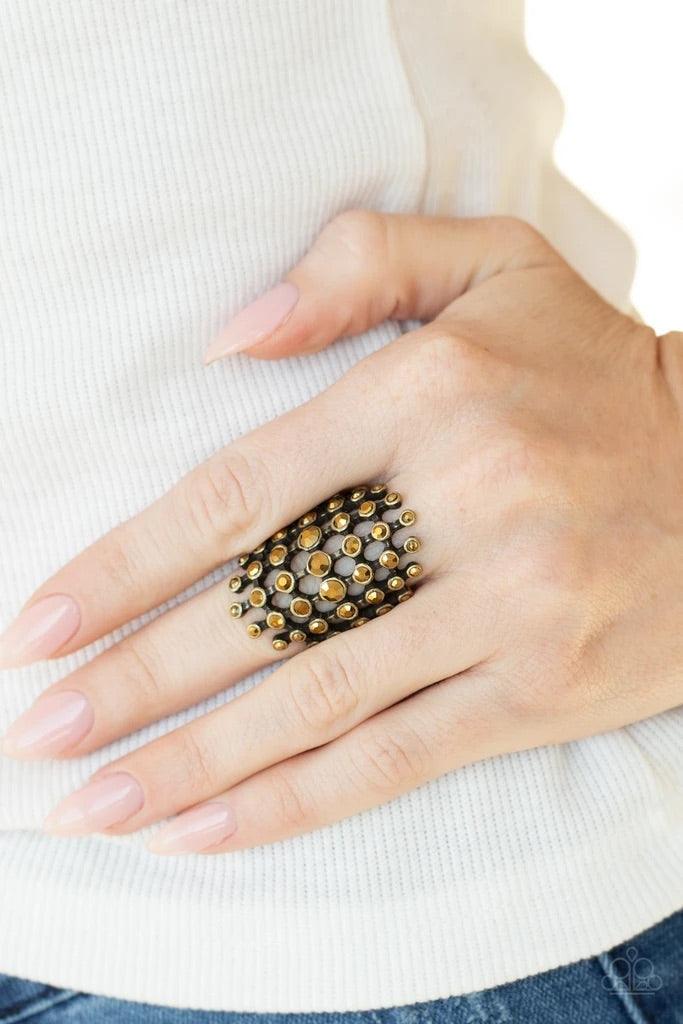 Paparazzi Accessories Fiercely Flashy - Brass Featuring glistening brass fittings, a sparkly series of aurum rhinestones interlock into an edgy grid across the finger for a spellbinding look. Features a stretchy band for a flexible fit. Jewelry