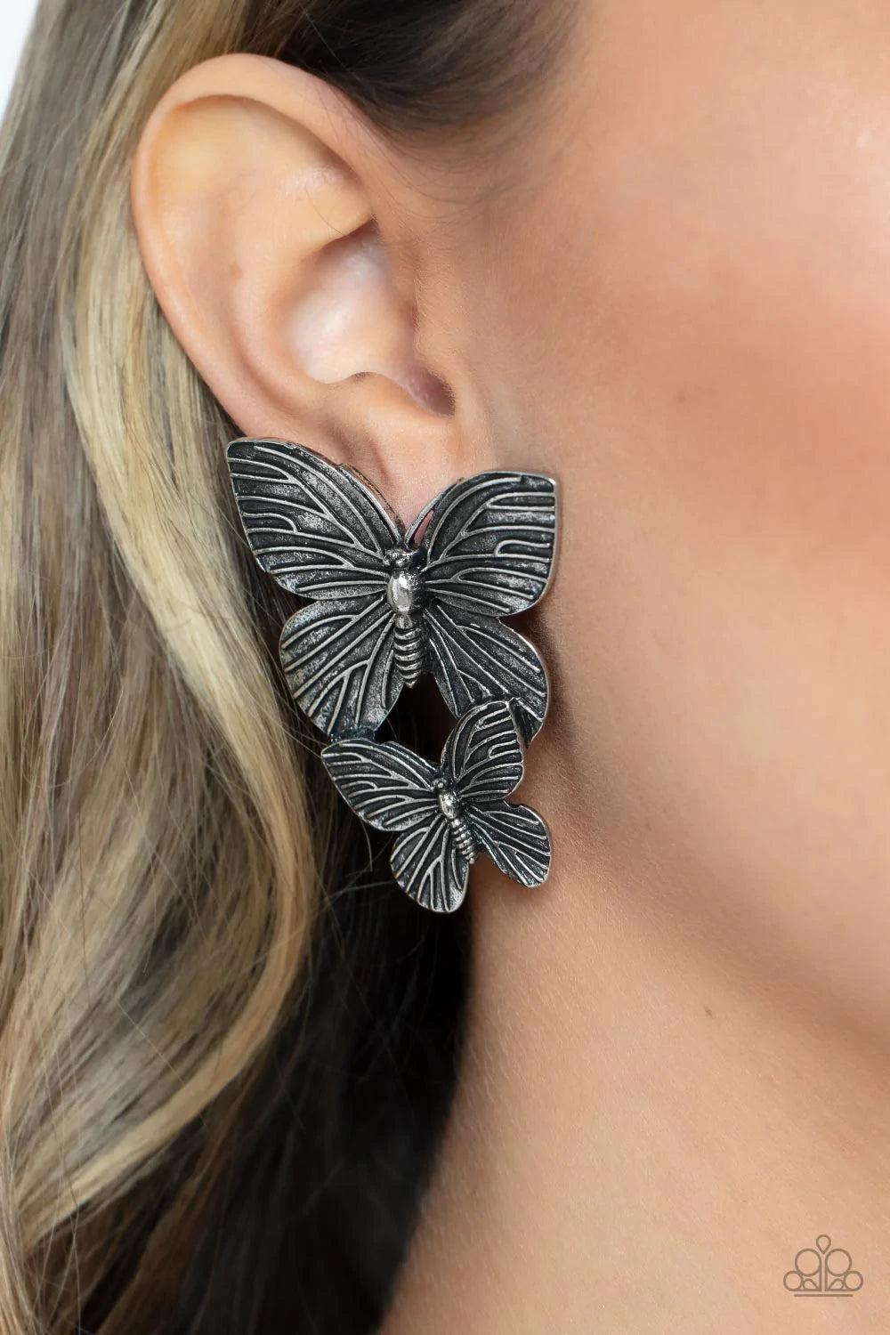 Paparazzi Accessories Blushing Butterflies - Silver Veined with lifelike textures, a pair of rustic silver butterflies flutters from the ear for a whimsical fashion. Earring attaches to a standard post fitting. Sold as one pair of post earrings. Jewelry