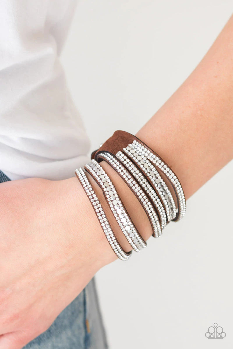 Paparazzi Accessories Rock Star Attitude - Brown Encrusted in rows of glassy white rhinestones and flat silver studs, three strands of brown suede wrap around the wrist for a sassy look. The elongated band allows for a trendy double wrap around the wrist.
