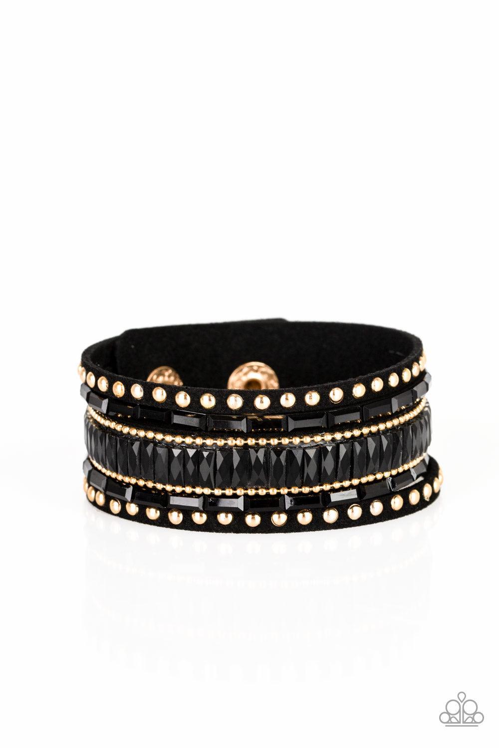 Paparazzi Accessories Rock Star Rocker - Gold Shiny gold studs, dainty gold ball chains, and edgy black emerald-cut rhinestones race along a spliced black suede band for a rock star look. Features an adjustable snap closure. Jewelry