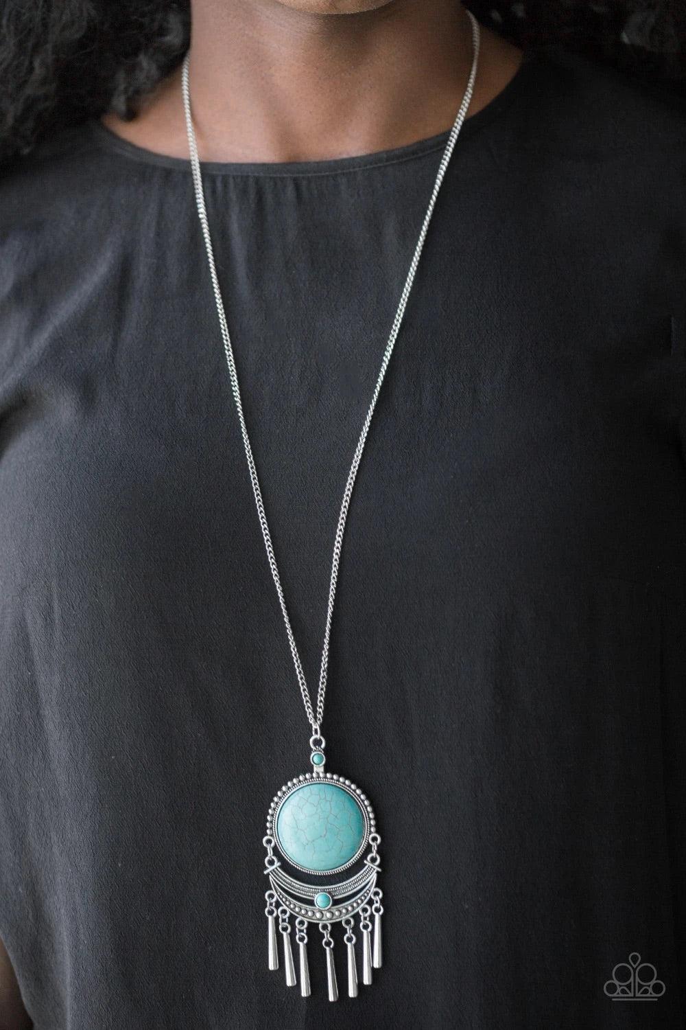 Paparazzi Accessories Rural Rustler - Blue Swinging from the bottom of a lengthened silver chain, a dramatic turquoise stone gives way to an ornate crescent shaped frame dotted with a dainty turquoise stone. Brushed in an antiqued shimmer, flared silver b