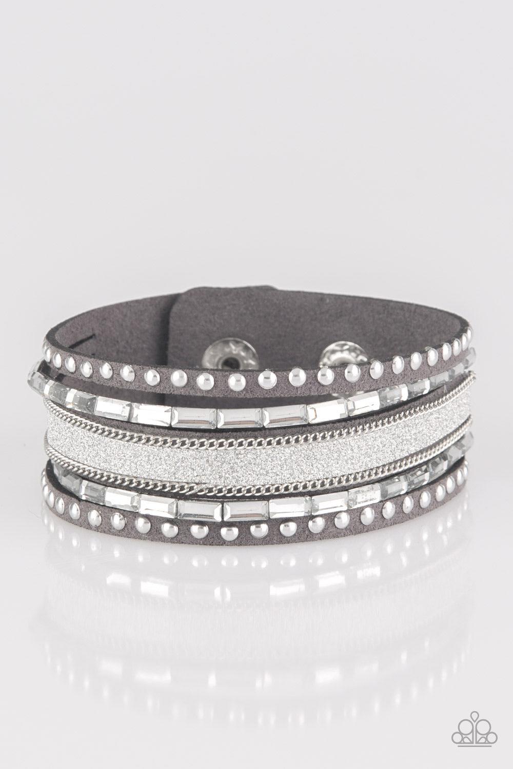 Paparazzi Accessories Seize The Sass - Silver Shimmery silver studs, dainty silver chains, and white emerald style cut rhinestones are encrusted along a gray suede band dusted in a sparkling center for a sassy look. Features an adjustable snap closure. So