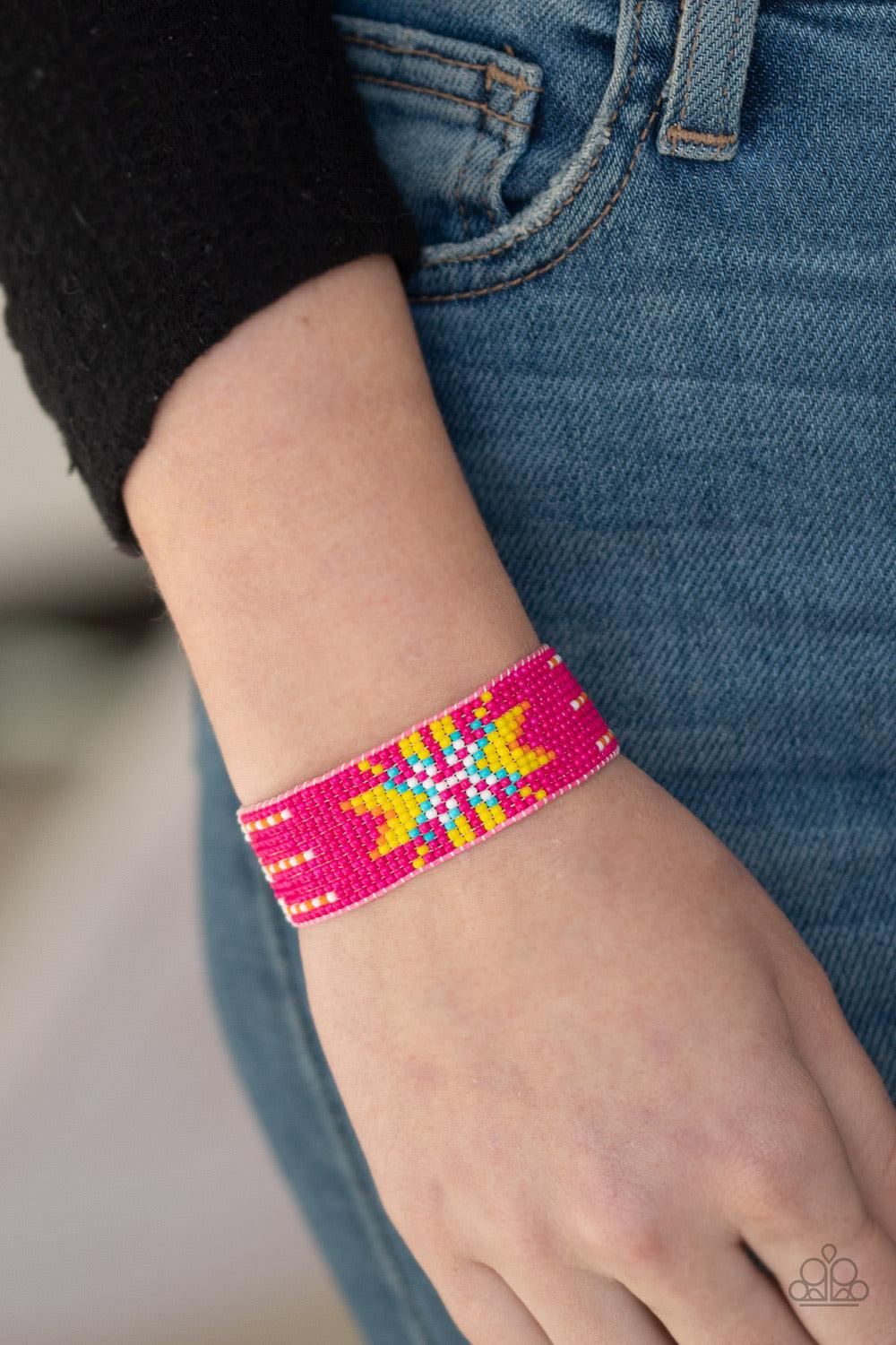 Paparazzi Accessories Beautifully Badlands - Pink Threaded along invisible thread, a dainty collection of pink, white, orange, yellow, and blue seed beads weave into a colorful textile pattern across the wrist for a tribal inspired look. Features an adjus