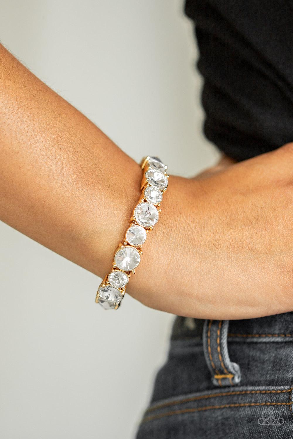 Paparazzi Accessories Born To Bedazzle - Gold An assortment of oversized white rhinestones are pressed into gold square frames and threaded along stretchy bands, creating a blinding sparkle around the wrist. Jewelry