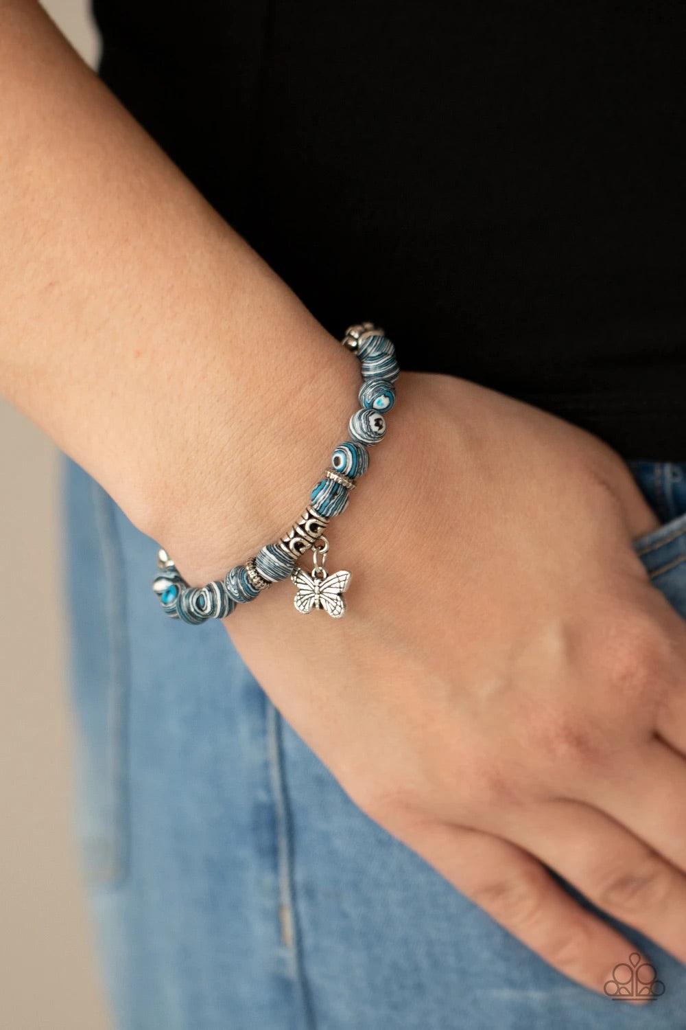Paparazzi Accessories Butterfly Wishes - Blue Swirling with blue, black, and white accents, colorful stone beads and ornate silver accents are threaded along stretchy bands around the wrist. A dainty silver butterfly charm dangles from the display, adding
