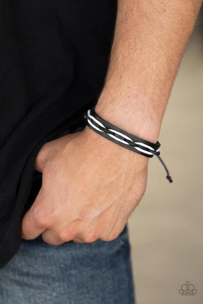 Paparazzi Accessories Lucky Locomotion - Black Black and white cording is interwoven across the top of a black leather band creating an edgy crisscrossed motion as it travels around the wrist. Features an adjustable sliding knot closure. Sold as one indiv