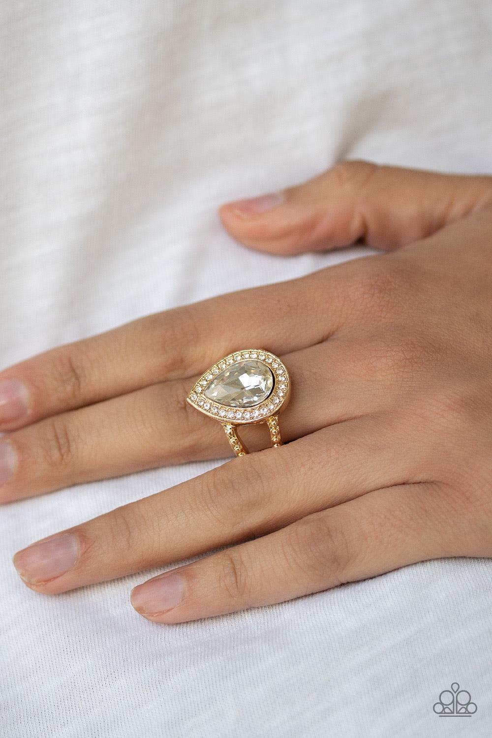 Paparazzi Accessories Hollywood Heirloom ~Gold A glassy white teardrop gem is pressed into a glistening gold frame encrusted in dainty white rhinestones, creating a glamorous frame atop the finger. Features a dainty stretchy band for a flexible fit.