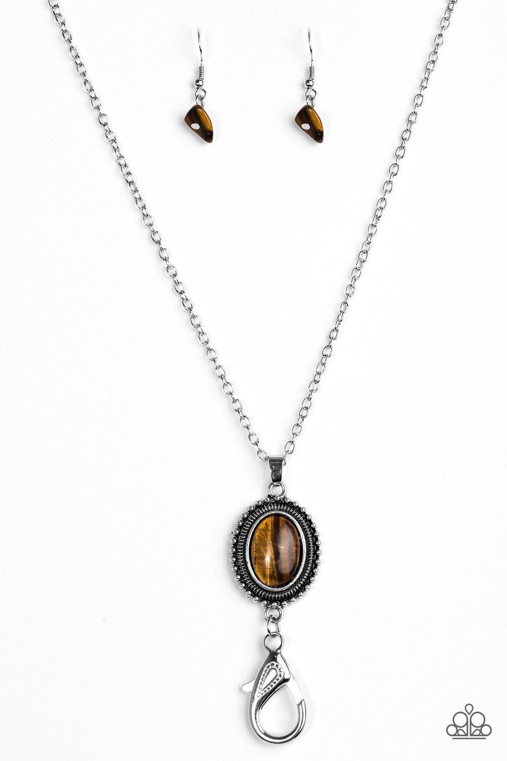 Paparazzi Accessories Canyon Climb - Brown *Lanyard A refreshing brown stone swings from the bottom of a lengthened silver chain, creating an earthy pendant. A lobster clasp hangs from the bottom of the design to allow a name badge or other item to be att