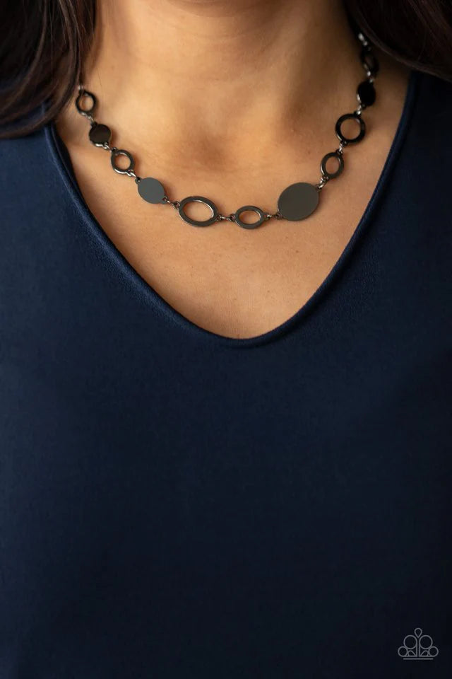 Paparazzi Accessories Working Oval Time - Black A shiny series of glistening gunmetal discs and oval frames delicately link below the collar, creating a casual statement. Features an adjustable clasp closure. Sold as one individual necklace. Includes one