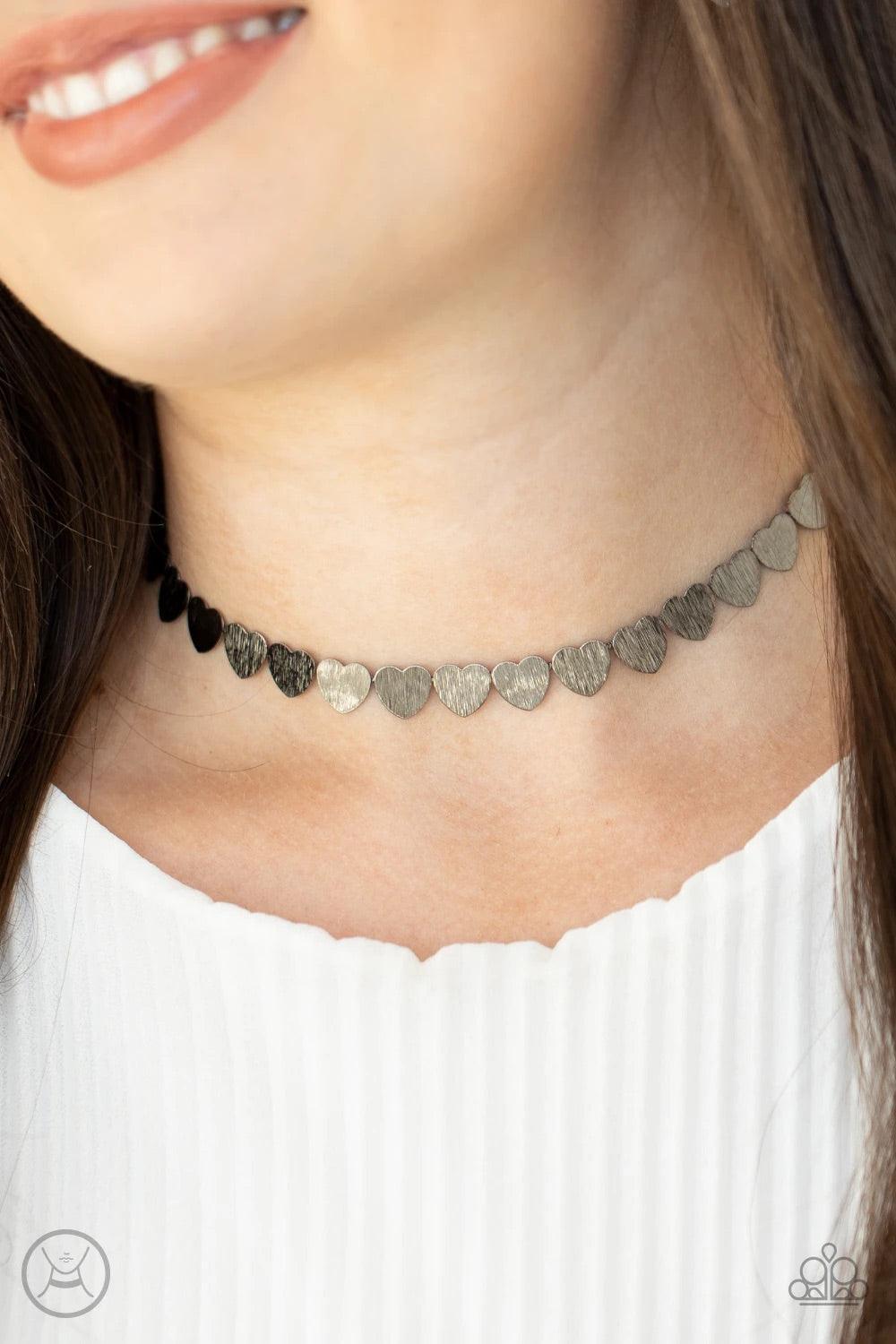 Paparazzi Accessories Playing HEART To Get - Black Featuring a shimmery scratch finish, a dainty collection of shiny gunmetal heart frames connect around the neck for a flirtatious look. Feature an adjustable clasp closure. Sold as one individual choker n