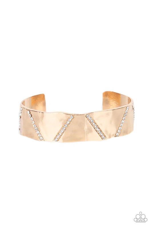 Paparazzi Accessories Couture Crusher - Gold Rows of glassy white rhinestones slant across the front of a gently hammered gold cuff that waves around the wrist, result in an edgy shimmer. Sold as one individual bracelet.