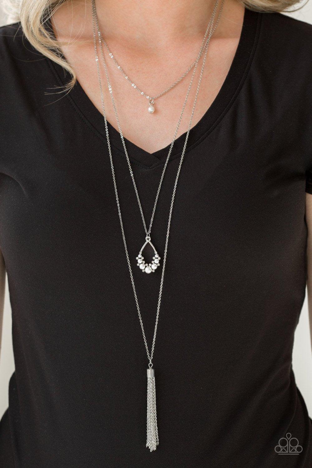 Paparazzi Accessories Be Fancy - White A solitaire white pearl swings from the uppermost chain, giving way to a teardrop pendant and shimmery silver chain tassel. Dainty white rhinestones and white pearls collect at the bottom of the centermost pendant fo