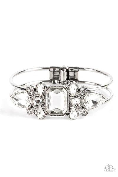 Paparazzi Accessories Call Me Old-Fashioned - White A blinding collection of round and marquise-cut white rhinestones are encrusted across the front of a shiny silver bar, curling around the wrist to create a timeless cuff-like bangle. Features a hinged c