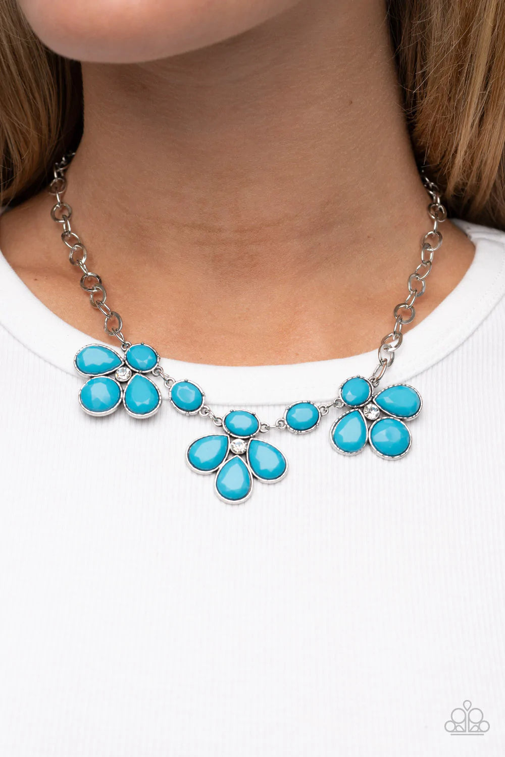 Paparazzi Accessories SELFIE-Worth - Blue Encased in textured silver fittings, oversized oval and teardrop blue beads delicately gather around glassy white rhinestone centers for a colorful floral look below the collar. Features an adjustable clasp closur