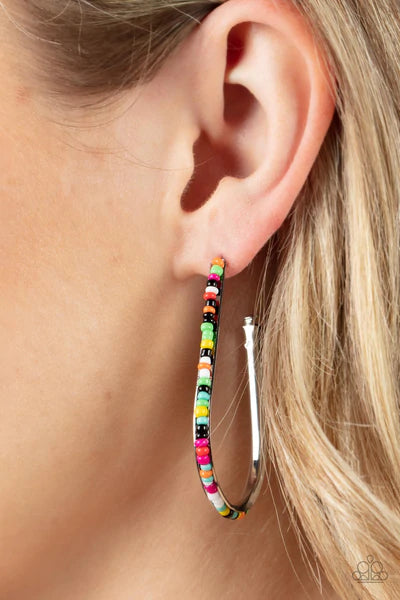 Paparazzi Accessories Beaded Bauble - Multi A dainty collection of multicolored seed beads embellish the beveled spine of a silver hook shaped hoop, creating a trendy pop of color. Hoop measures approximately 1 1/2" in diameter. Earring attaches to a stan