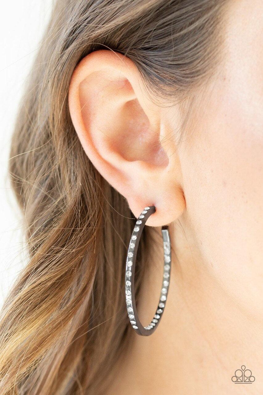 Paparazzi Accessories Comin’ Into Money - Black The front half and inner backside of a sleek gunmetal hoop is encrusted in glassy white rhinestones, easily catching and reflecting the light for an extra dash of shimmer. Earring attaches to a standard post