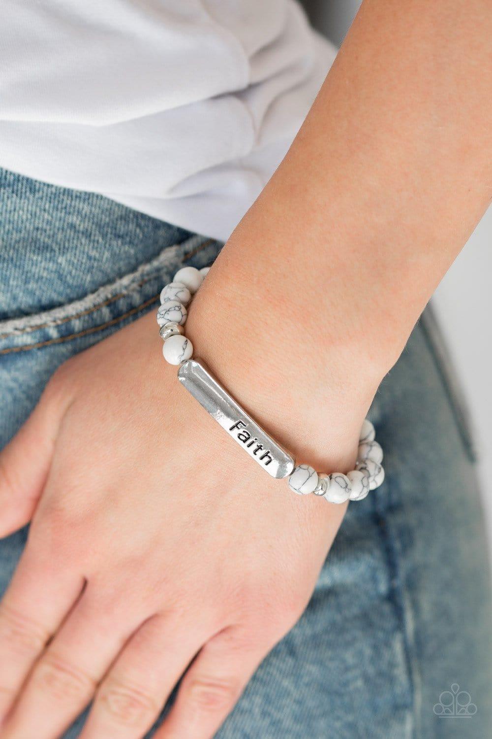Paparazzi Accessories Fearless Faith - White Infused with dainty silver beads, refreshing white stone beads and a glistening silver plate stamped with the inspirational word, "Faith", are threaded along a stretchy band for a seasonal look. Sold as one ind