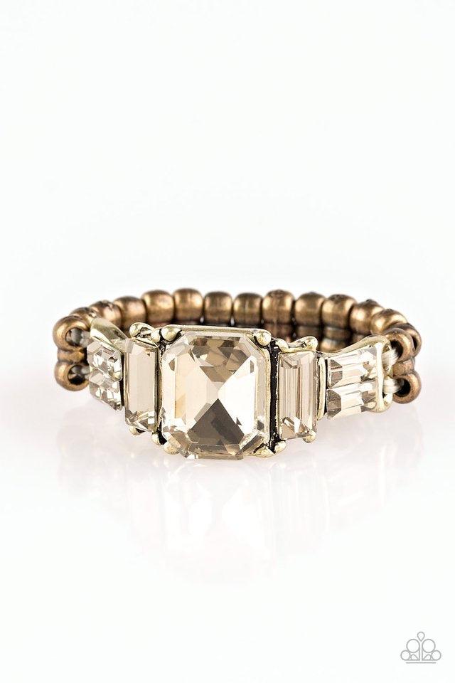 Paparazzi Accessories Born To Rule - Brass Varying in cut and shimmer, glittery rhinestones stack into a glamorous band across the finger. Features a dainty stretchy band for a flexible fit. Jewelry