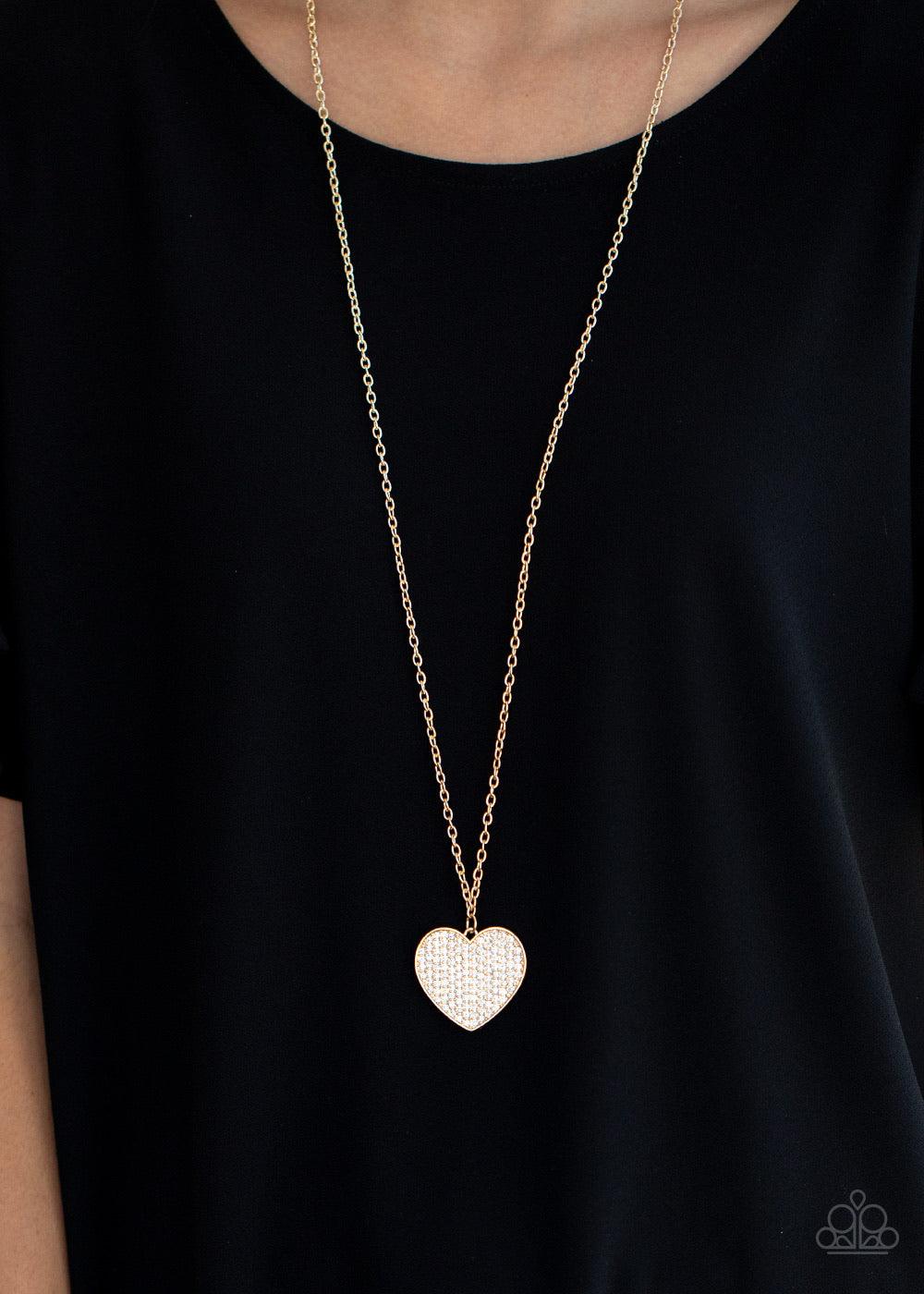 Paparazzi Accessories Have To Learn The HEART Way - Gold Encrusted in row after row of glassy white rhinestones, a dazzling gold heart swings from the bottom of a lengthened gold chain for a charming finish. Features an adjustable clasp closure. Sold as o