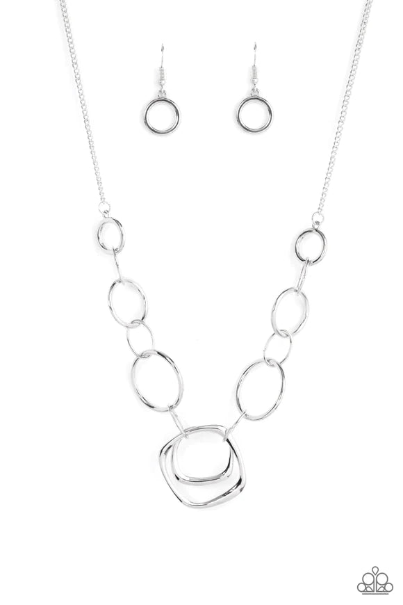 Paparazzi Accessories Linked Up Luminosity - Silver A mismatched collection of silver rings and asymmetrical silver hoops delicately links below the collar, resulting in a modern industrial display. Features an adjustable clasp closure. Sold as one indivi