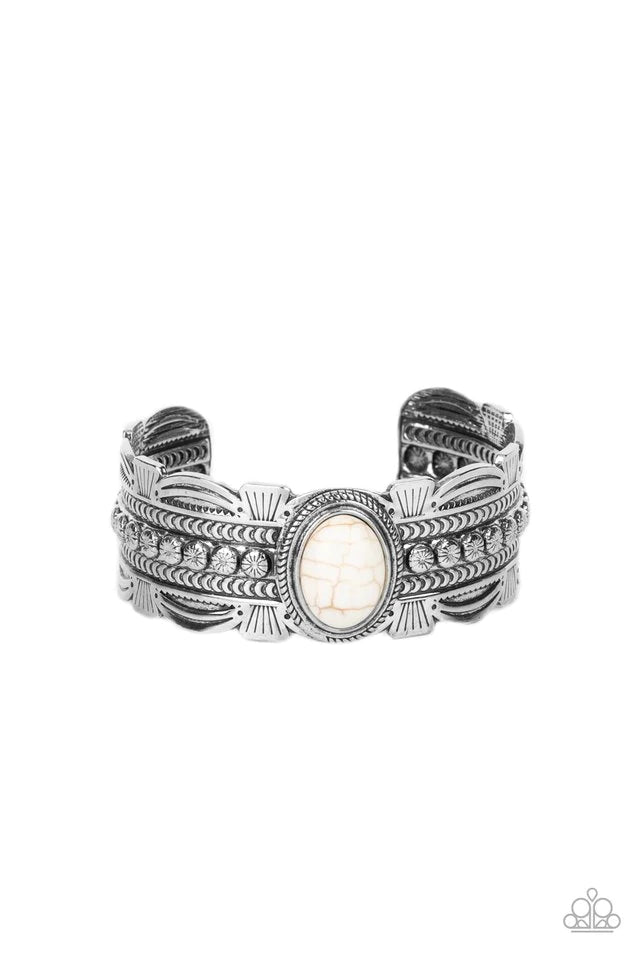 Paparazzi Accessories Desert Stroll - White An oversized oval white stone is pressed into the studded center of an ornate silver cuff stamped and embossed in tribal inspired patterns, resulting in a refreshing pop of color atop the wrist. Sold as one indi