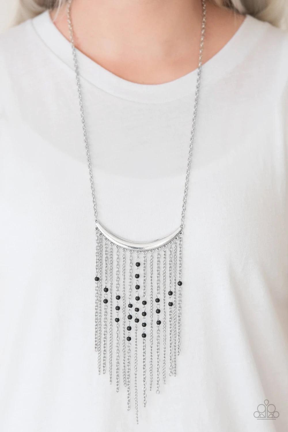 Paparazzi Accessories Runaway Rumba - Black Glistening silver chains stream from the bottom of a shiny silver crescent, creating a bold tapered fringe down the chest. Dainty black stone beads sporadically trickle down the chains for a seasonal finish. Fea