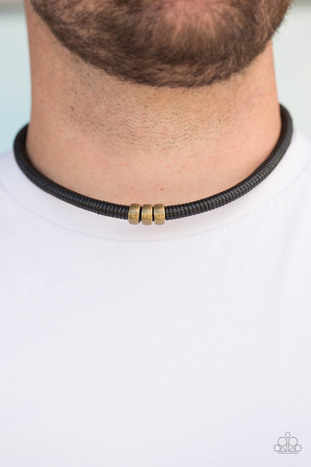 Paparazzi Accessories Trail Rules - Brass Shiny black twine wraps around a black cord, creating an urban look below the collar. Shiny brass beads slide along the cording for a rugged finish. Features a button loop closure. Sold as one individual necklace.