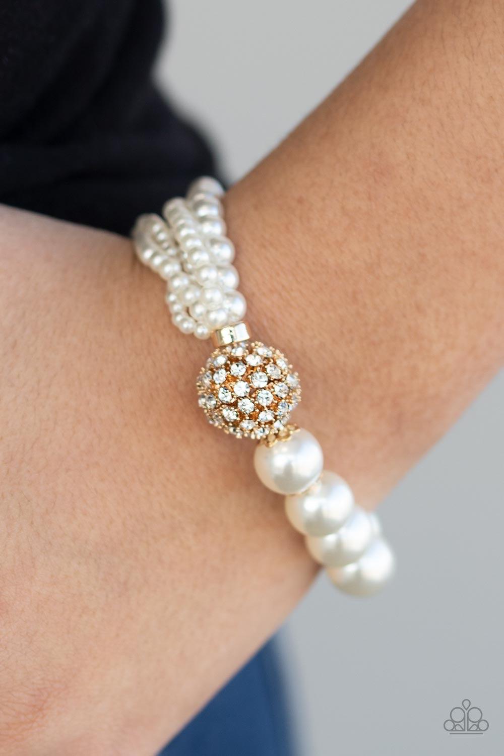 Paparazzi Accessories Vintage Collision - Gold Featuring stretchy bands, a white rhinestone encrusted gold bead joins together strands of mismatched pearls and a single strand of classic white pearls around the wrist for a timeless twist. Jewelry