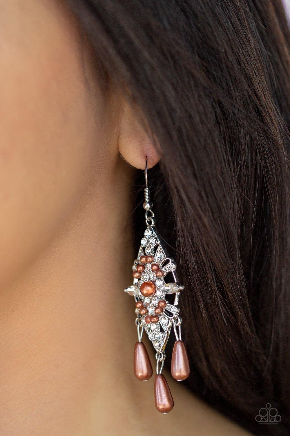 Paparazzi Accessories Majestic Mood - Brown Dotted with dainty brown pearls, a silver kite-shaped frame is encrusted in glassy white rhinestones. Teardrop pearls swing from the bottom of the sparkling frame for a refined flair. Earring attaches to a stand