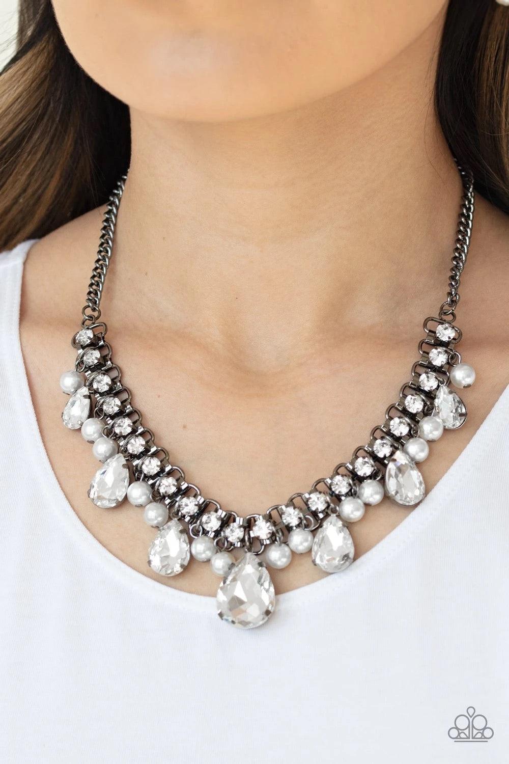 Paparazzi Accessories Knockout Queen - Black A glamorous collection of bubbly white pearls and exaggerated white teardrop gems dangle from a bold strand of white rhinestones, creating a knockout fringe below the collar. Features an adjustable clasp closur