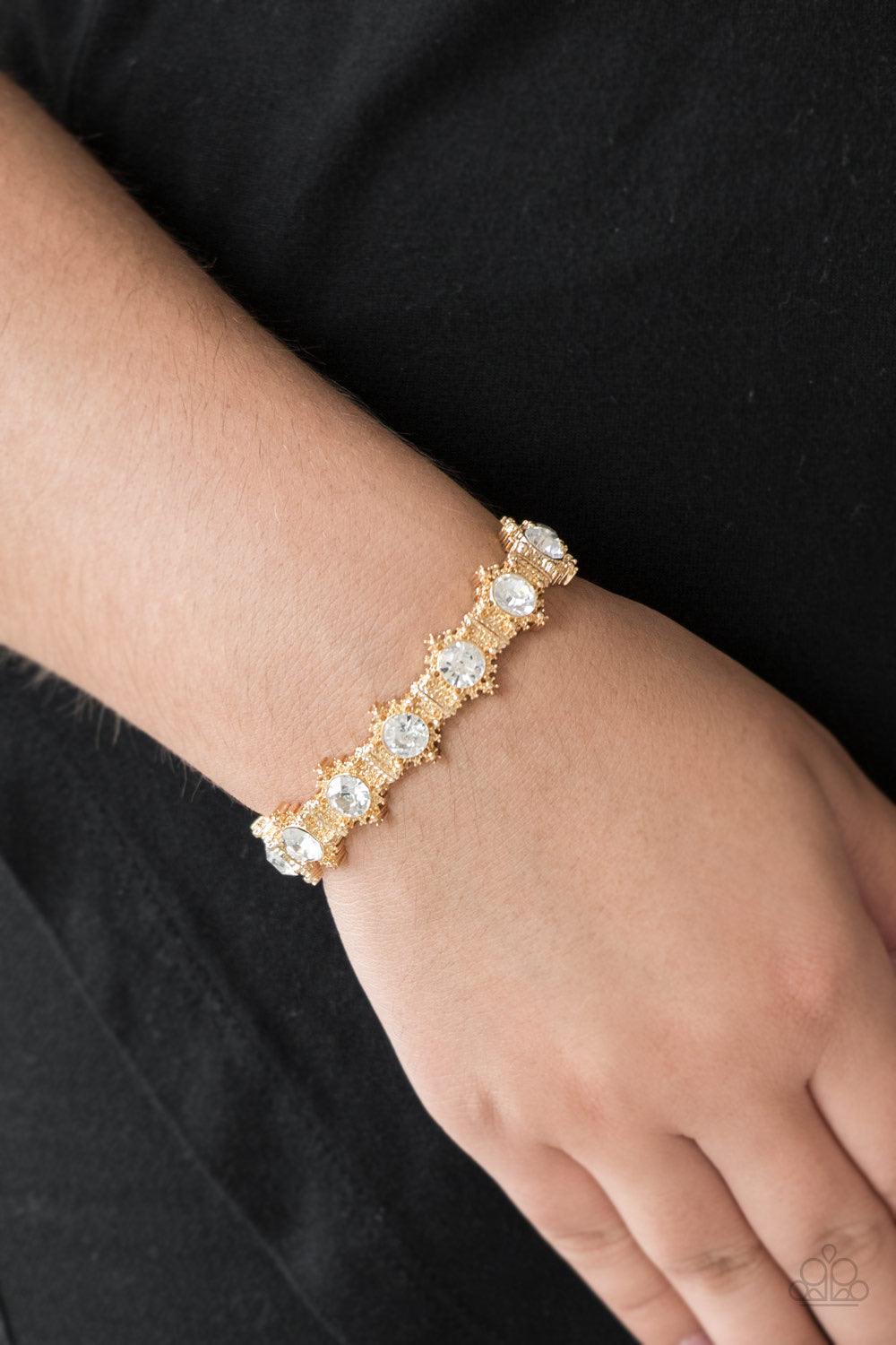 Paparazzi Accessories Strut Your Stuff - Gold Featuring glittery white rhinestone centers, ornate golden frames are threaded along stretchy bands, linking across the wrist for a refined look. Jewelry
