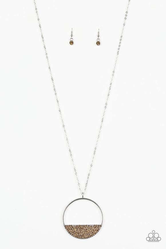 Paparazzi Accessories Set Your Bottom Dollar - Brown Encrusted in golden topaz rhinestones, a silver crescent frame is pressed into the bottom of an airy circular pendant for a timeless look. Features an adjustable clasp closure. Sold as one individual ne