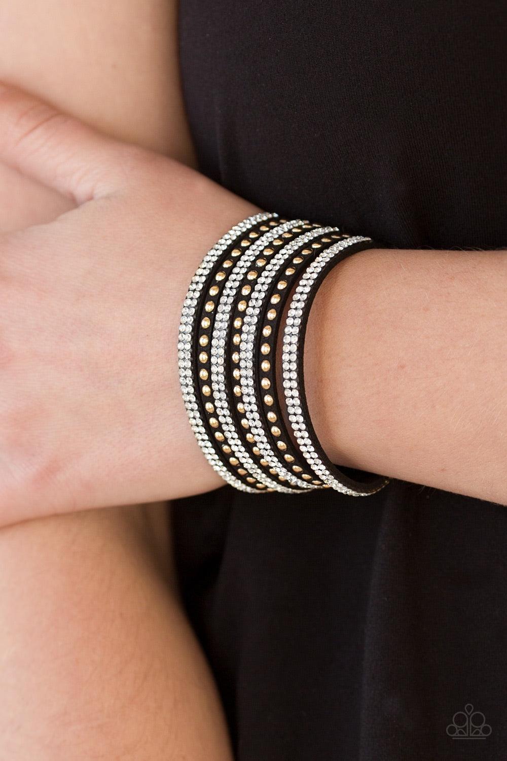 Paparazzi Accessories Victory Shine - Black Shiny gold studs and rows of glittery white rhinestones are encrusted along strips of black suede, creating sassy shimmer around the wrist. Features an adjustable snap closure. Jewelry