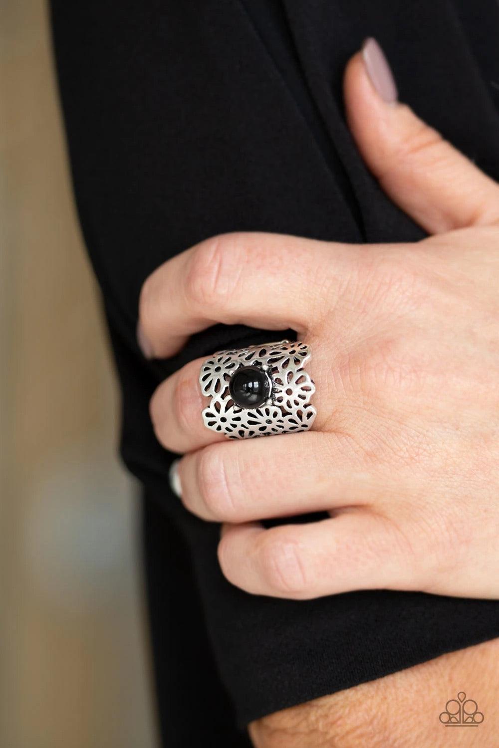 Paparazzi Accessories Flower Shower - Black A collection of airy silver flowers coalesce into a thick silver band. A polished black bead dots the center, adding a perfect pop of color to the seasonal piece. Features a stretchy band for a flexible fit. Sol